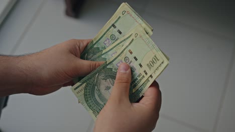 cerca de las manos masculinas contando una pila de cien mil guaraníes billetes de cerdo un hombre de negocios está contando efectivo el concepto de inversión, intercambio de dinero, sobornos o corrupción
