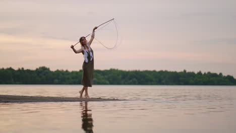 a young girl artist shows magic tricks using huge soap bubbles. create soap bubbles using sticks and rope at sunset to show a theatrical circus show