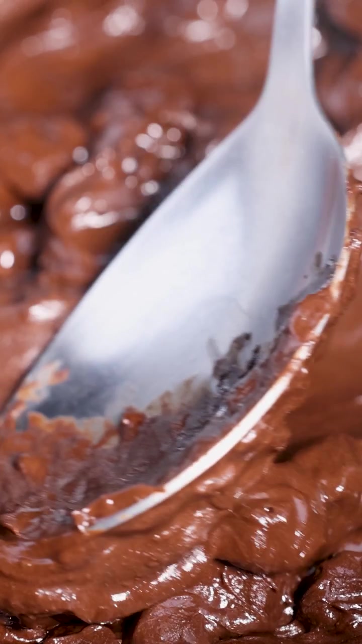 Cucchiaio che mescola cioccolato fuso in una ciotola di metallo