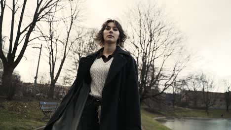 Young-woman-in-a-black-coat-walking-in-a-park-in-autumn-in-afternoon-4