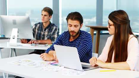 Graphic-designers-discussing-over-laptop-at-desk