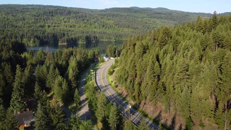 drone flying over winding road in rural forest countryside in canada