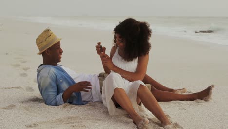 African-American-woman-clicking-photo-of-man-with-mobile-phone-on-the-beach-4k