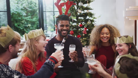 group of friends celebrating with champagne after enjoying christmas dinner at home