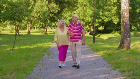 senior stylish pensioners couple grandmother grandfather walking, enjoying time together in park