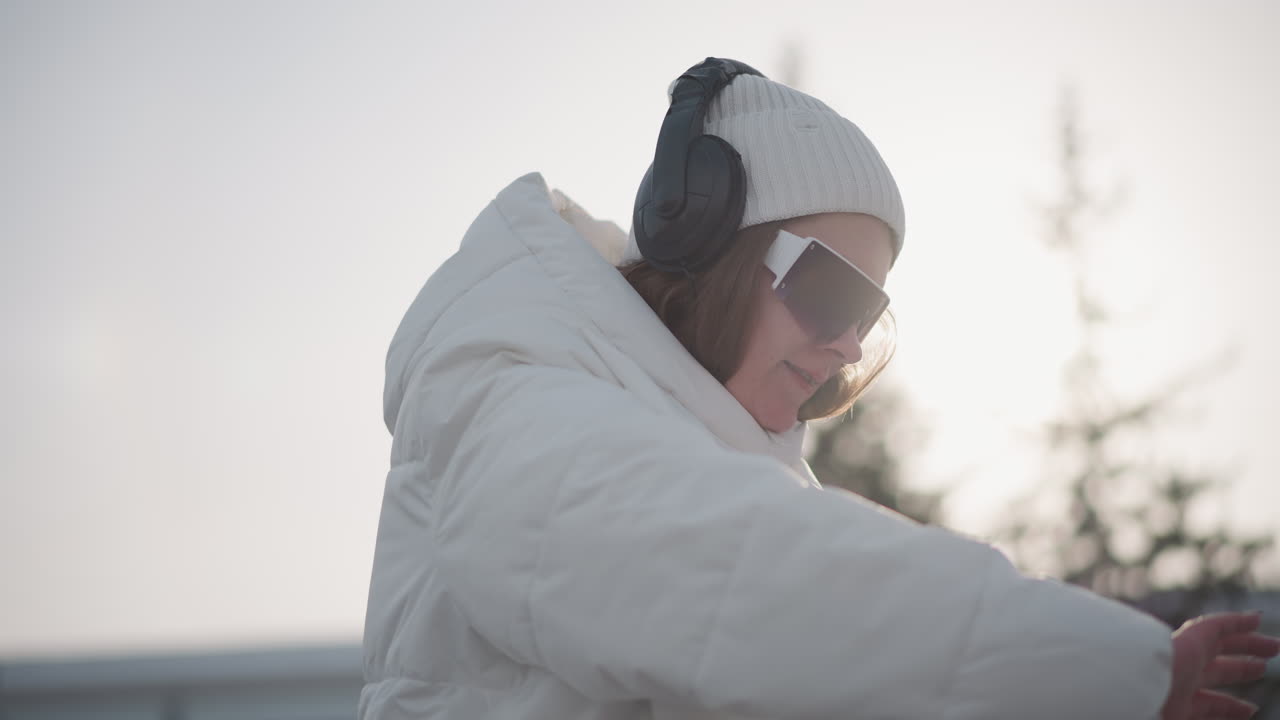 Young star dancing with boundless energy smiling under dark glasses wearing ear pod rhythmic movements conveying joyful expression vibrant beat driven performance captured outdoors sunlit