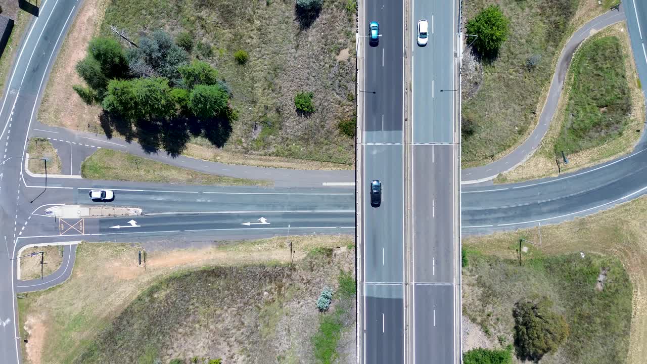 Drone aerial landscape of car vehicles traffic driving across freeway bridge overpass of road street grassy valley in Canberra ACT Australia transport tourism infrastructure automotive urban