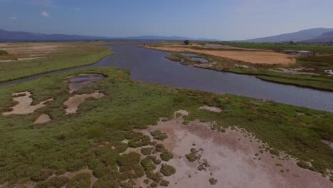 aerial: a river delta with a road-bridge passing through and some agricultural buildings