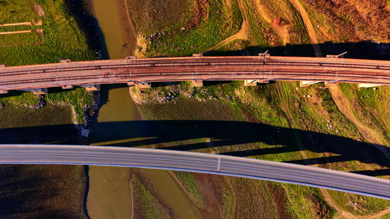 Ponti paralleli per treni e auto che attraversano un letto di fiume stretto. Vista aerea dall'alto di ponti ferroviari e stradali sul fiume.