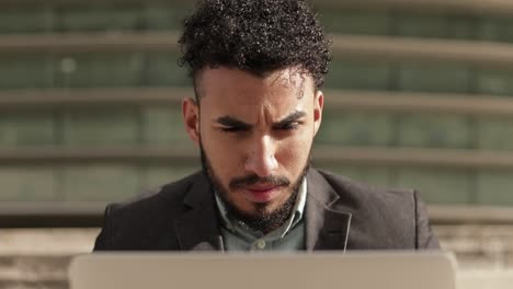 Concentrated-man-sitting-on-stairs-and-working-with-laptop