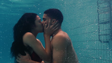 young couple kissing underwater in swimming pool enjoying intimate kiss romantic lovers submerged in water floating with bubbles in passionate intimacy