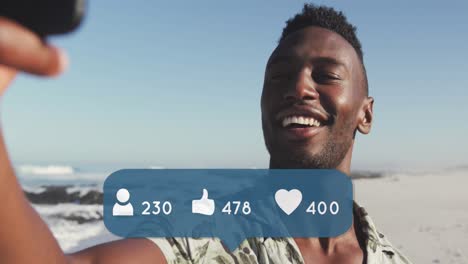 animation of people, thumbs up and heart icons over smiling man using smartphone on beach