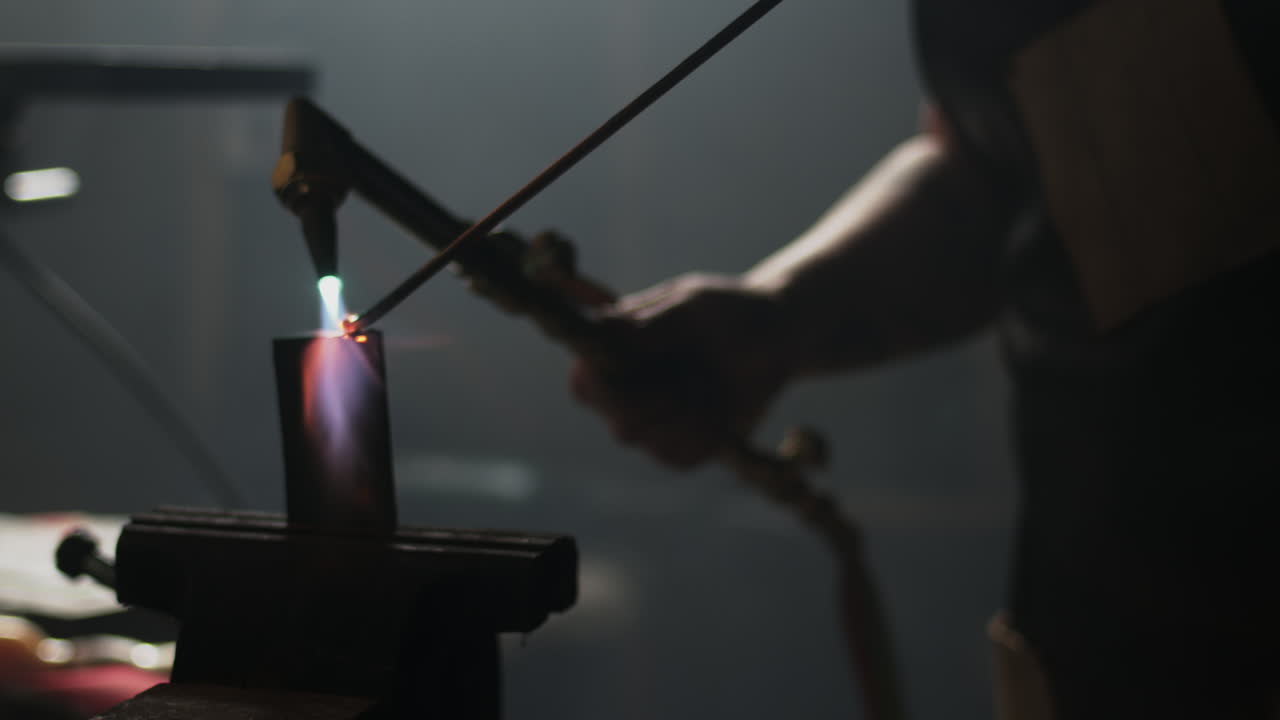 Slow motion welding a piece of metal in a vice on a bench in blacksmiths workshop
