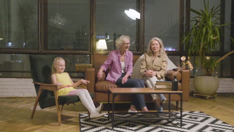 niñita jugando en la sala de estar mientras sus dos abuelas se sientan en el sofá y la miran