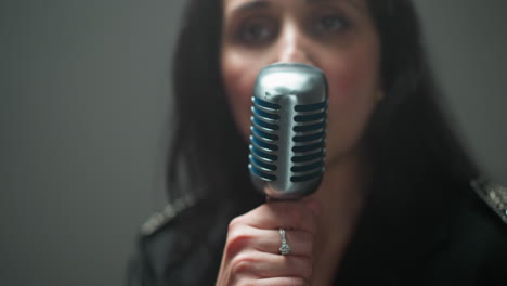 close-up of a vocalist with blurred focus, singing into a vintage microphone against a soft, blurred background with dynamic camera movement