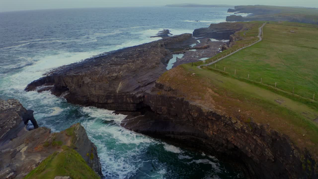 Aerial dolly of Bridges of Ross with waves revealing millions of years of erosion.