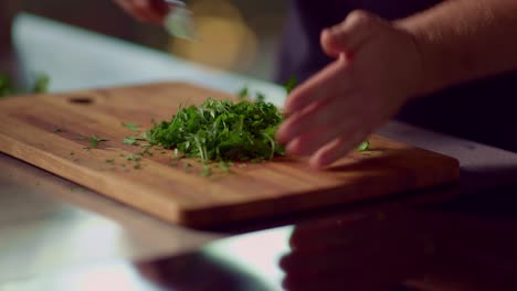 a man chops parsley on a wooden cutting board