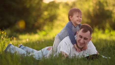 Liebevoller-Junger-Vater-Und-Sohn-Spielen-Im-Sommer-Bei-Sonnenuntergang-In-Zeitlupe-Auf-Dem-Gras.