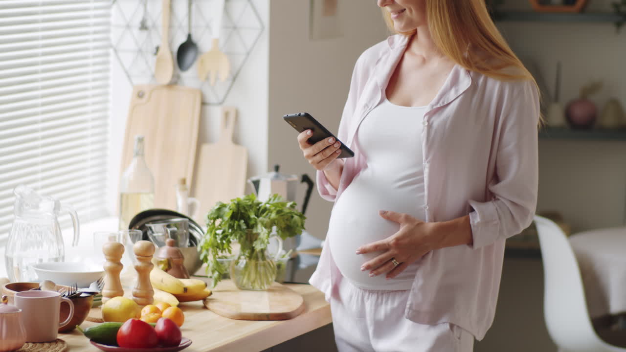 부에서 스마트폰으로 메시지를 보내는 임신한 여성