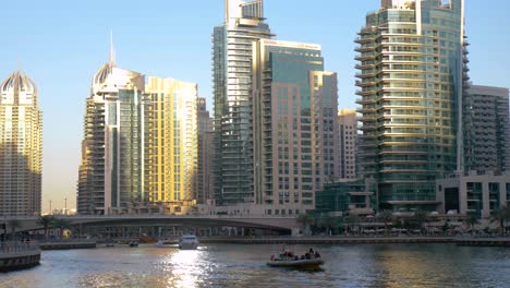 dubai marina, small rib boat on the water with high rise buildings with golden sunlight