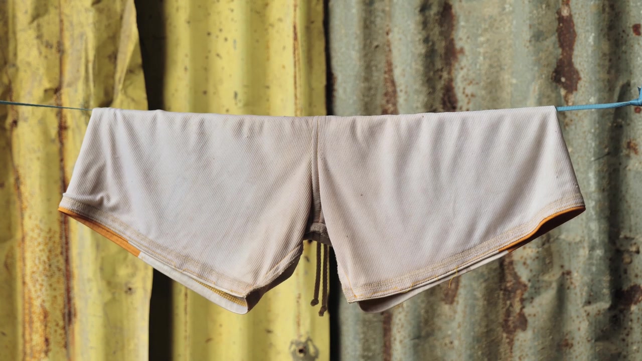 Primo piano, pantaloncini appesi al filo con una parete di metallo ondulato dietro, Filippine.