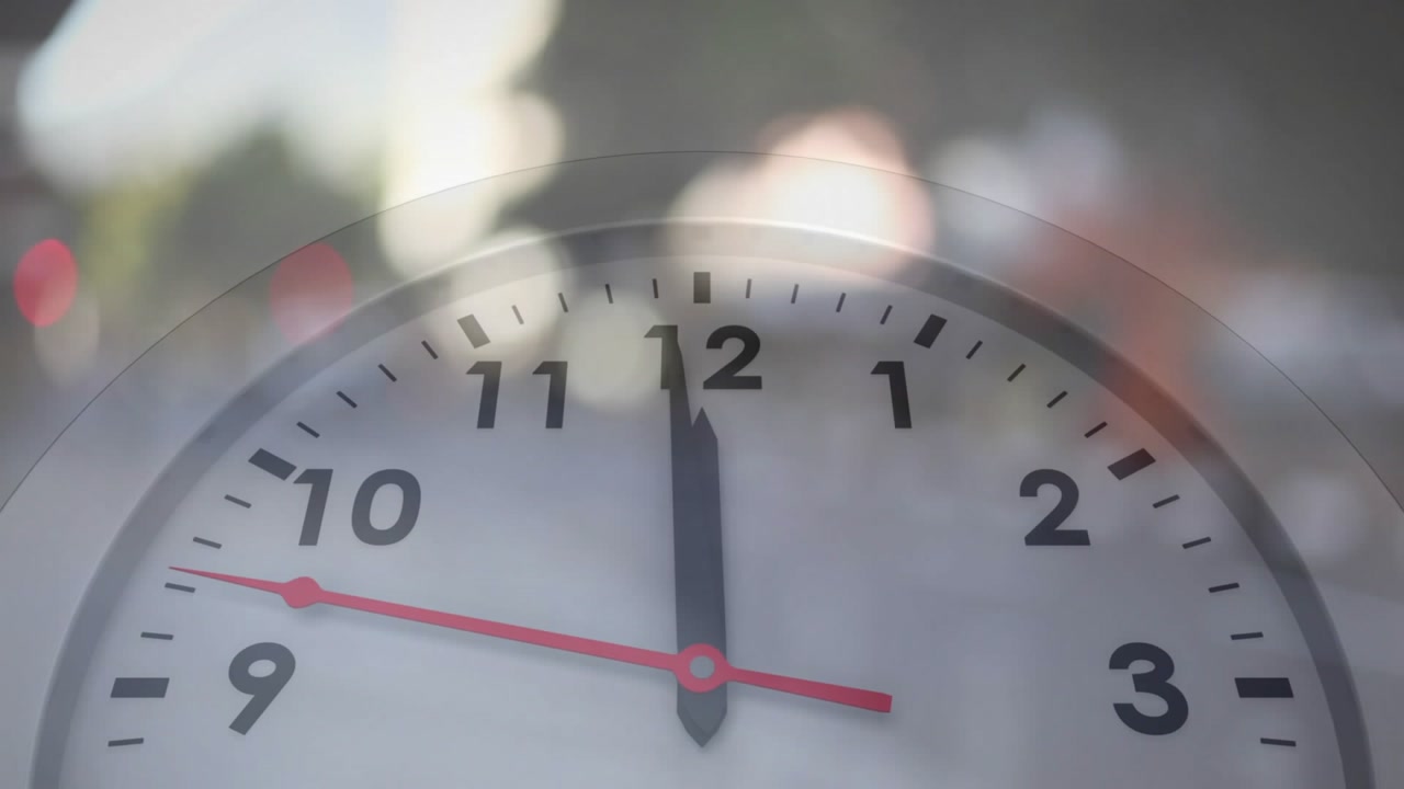 Clock face appearing with blurred street background, red second hand moving clockwise marking time