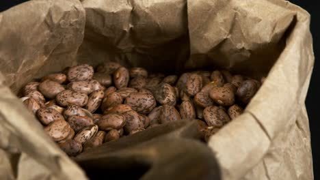 frijoles pinto secos manchados en una bolsa de papel giran en una vista macro de primer plano