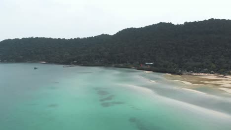 wide view of saracen bay seaside displaying the turquoise shallow waters and tropical vegetation - aerial panoramic wide shot