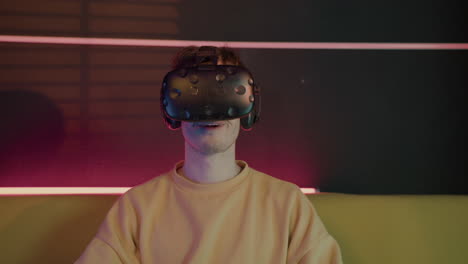 Aufgeregter-Junge,-Der-Videospiele-Spielt,-Eine-Virtual-Reality-Brille-Trägt-Und-Gamepads-Verwendet,-Die-Zu-Hause-Auf-Dem-Sofa-Sitzen