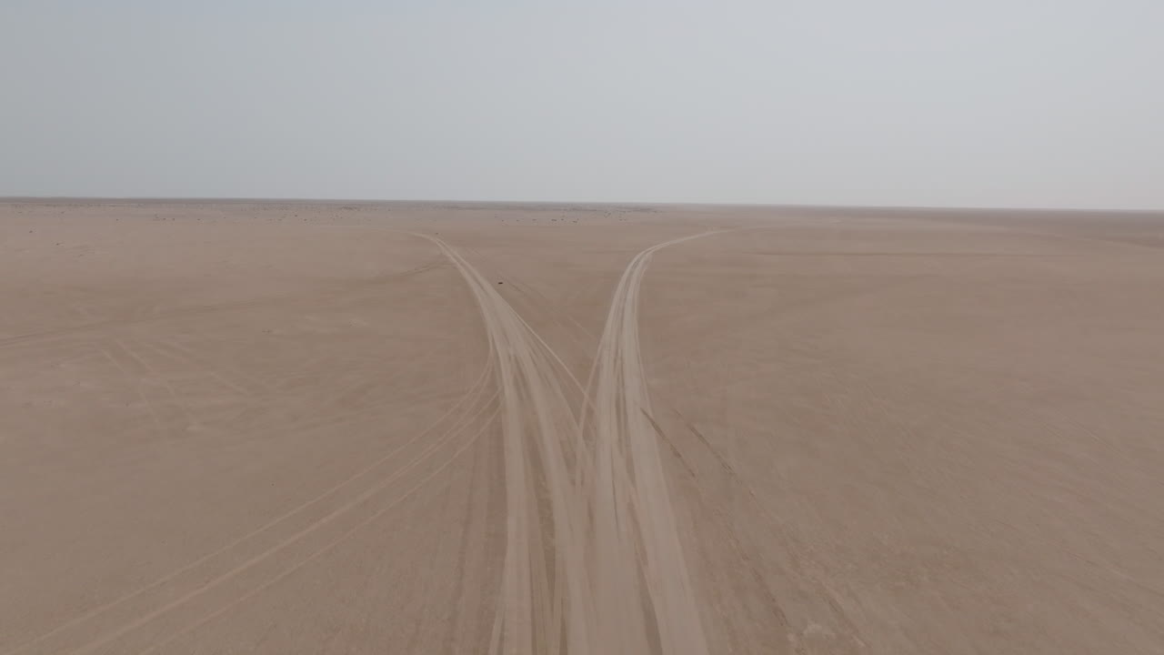 Empty desert road tracks leading to Bar al Hikman, Oman, captured from above
