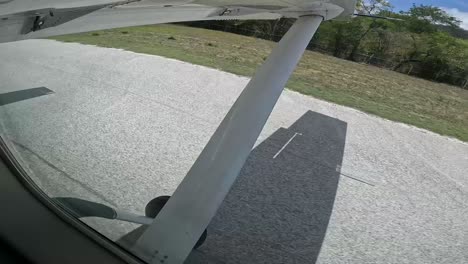 single engine airplane landing on rural costa rican runway at midday, side window view