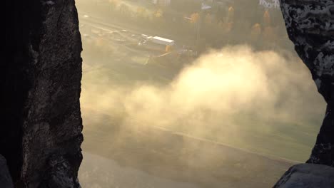 view from bastei bridge between rocks down to foggy elbe river, saxony