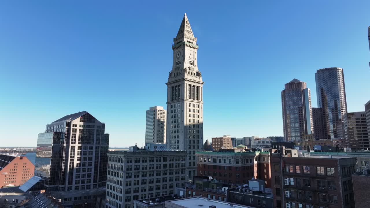 Custom House Tower stands tall in Boston’s Financial District. Surrounded by modern skyscrapers and views of Boston Harbor. Historic and urban architectural aerial.
