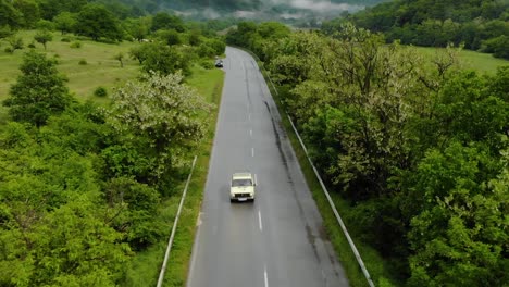 Vista-Aérea-De-Un-Camión-Que-Pasa-Por-Un-Vehículo-Estacionado-En-Una-Carretera-Rural---Dron-Descendente