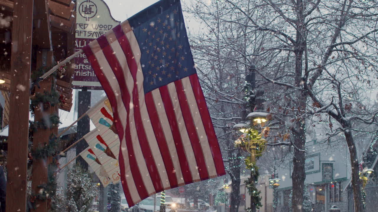 Coppia che attraversa una strada fiancheggiata da bandiere USA durante una nevicata natalizia e i festeggiamenti di Capodanno