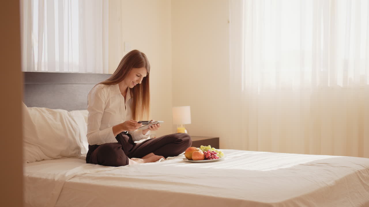 여자 는 호텔 방 에서 아침 식사 의 사진 을 찍고 있다