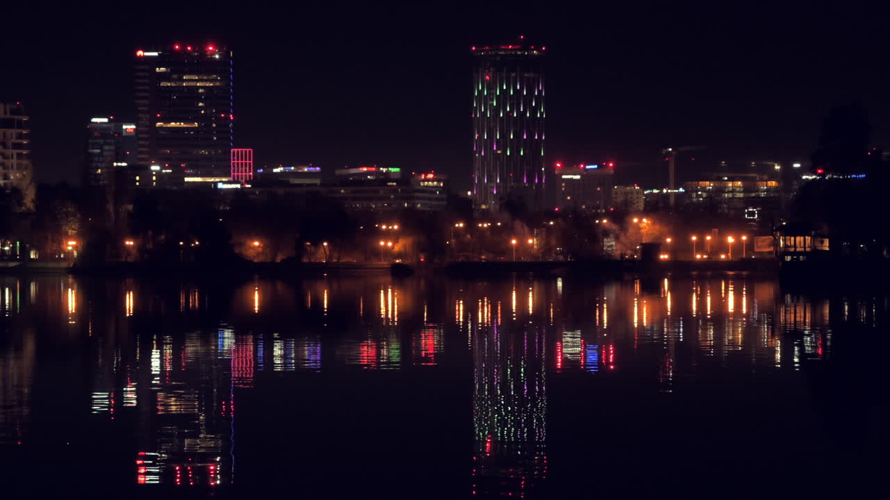 Lighted buildings reflected on the Herastrau Lake at night