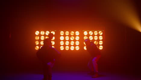 dancing team silhouette performing modern movements in nightclub backlight.