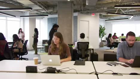 modern office workspace featuring collaborative environment with employees engaged in work activities and conversations amidst a bright, open layout