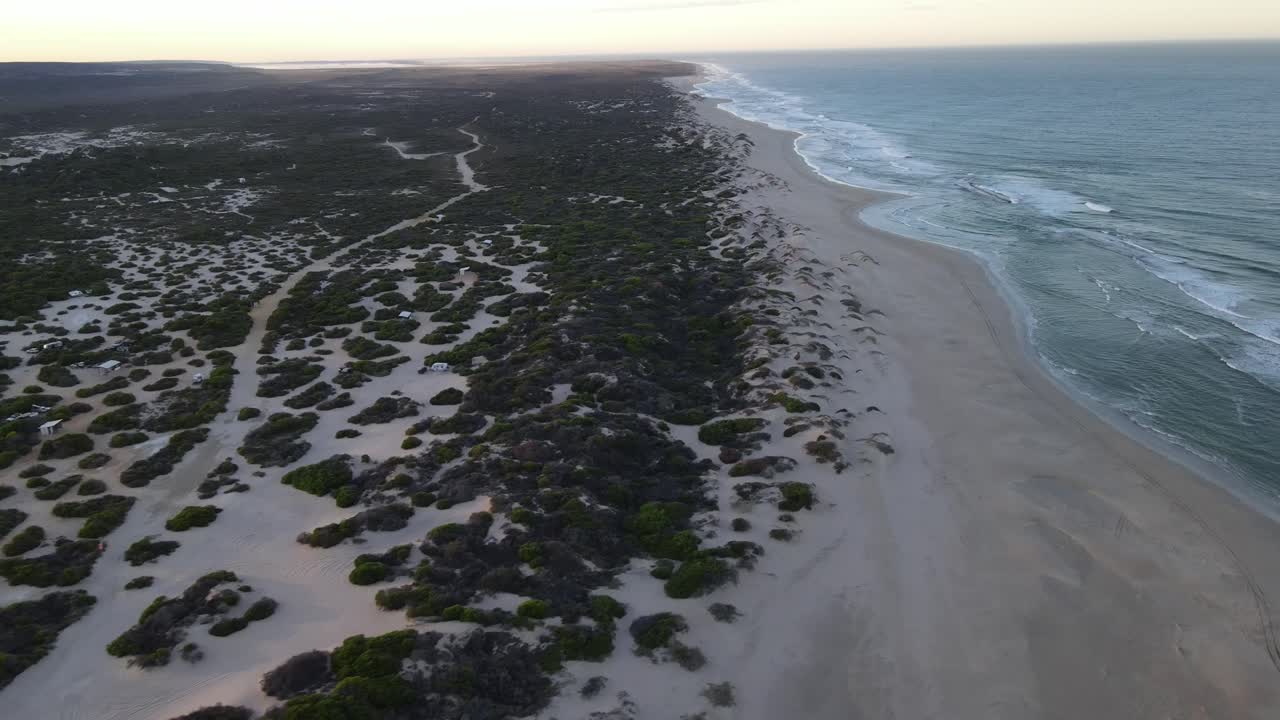Hohe Drohnenaufnahme über einem ruhigen, unberührten Strand bei Sonnenaufgang