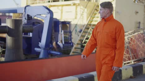 harbor worker in orange uniform is walking on cargo harbor site. slow motion