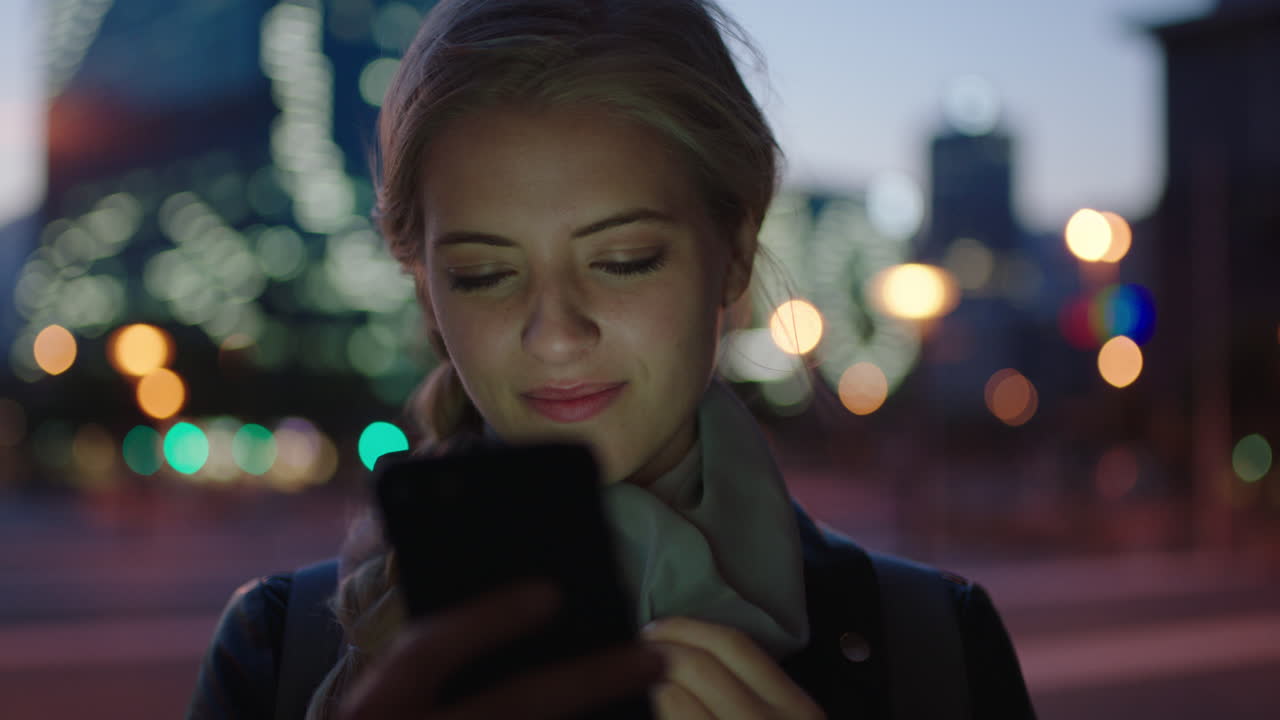 ritratto di una giovane donna bionda attraente che invia messaggi di testo navigando utilizzando un'app di social media per smartphone in attesa in una strada della città di notte godendosi una serata urbana tranquilla