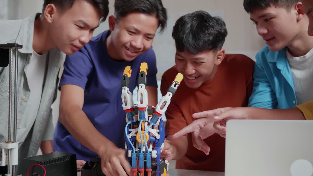 un grupo de jóvenes asiáticos con una computadora portátil e impresión 3d disfrutan comprobando una mano de cyborg en casa.