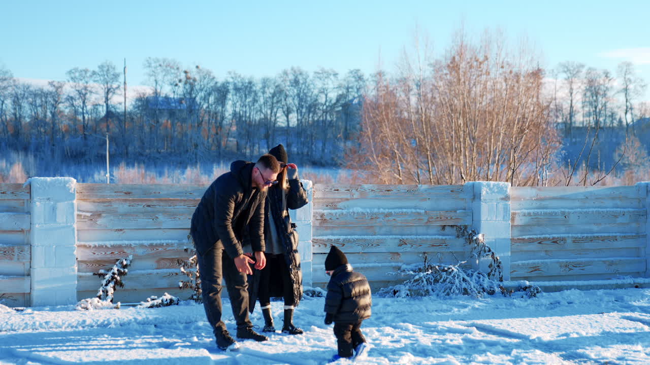 Happy man embraces his woman kissing her on the head. Baby boy walks up to dad and father takes his son to hands.