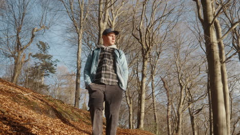 young man walking through a hilly forest on a sunny autumn day