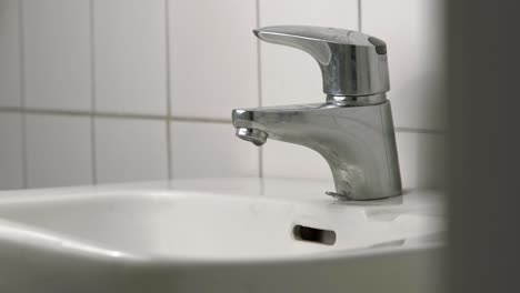 Water-dripping-from-dirty-faucet-in-bathroom