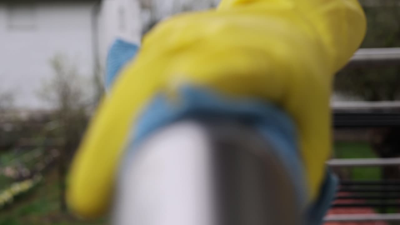 cerrar la mano de la mujer usando un trapo húmedo y un spray de desinfectante de manos para limpiar la barandilla de la escalera de acero inoxidable