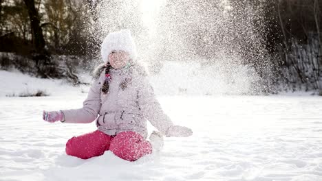 girl in a park is happy about throwing snow up