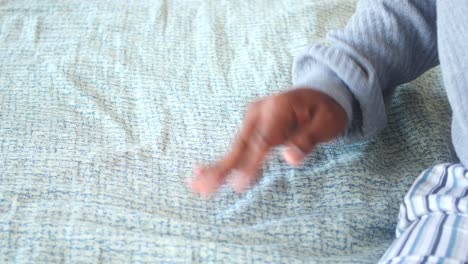 a person's hand reaching for the blanket on a bed