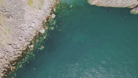 Toma-Aérea-De-Arriba-Hacia-Abajo-De-Agua-Hermosa,-Que-Revela-Una-Bahía-Y-Un-Acantilado